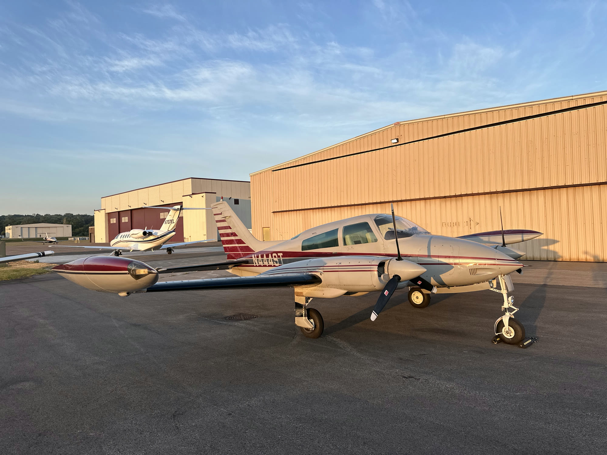N444ST parked on the ramp in golden evening light beside the hangars